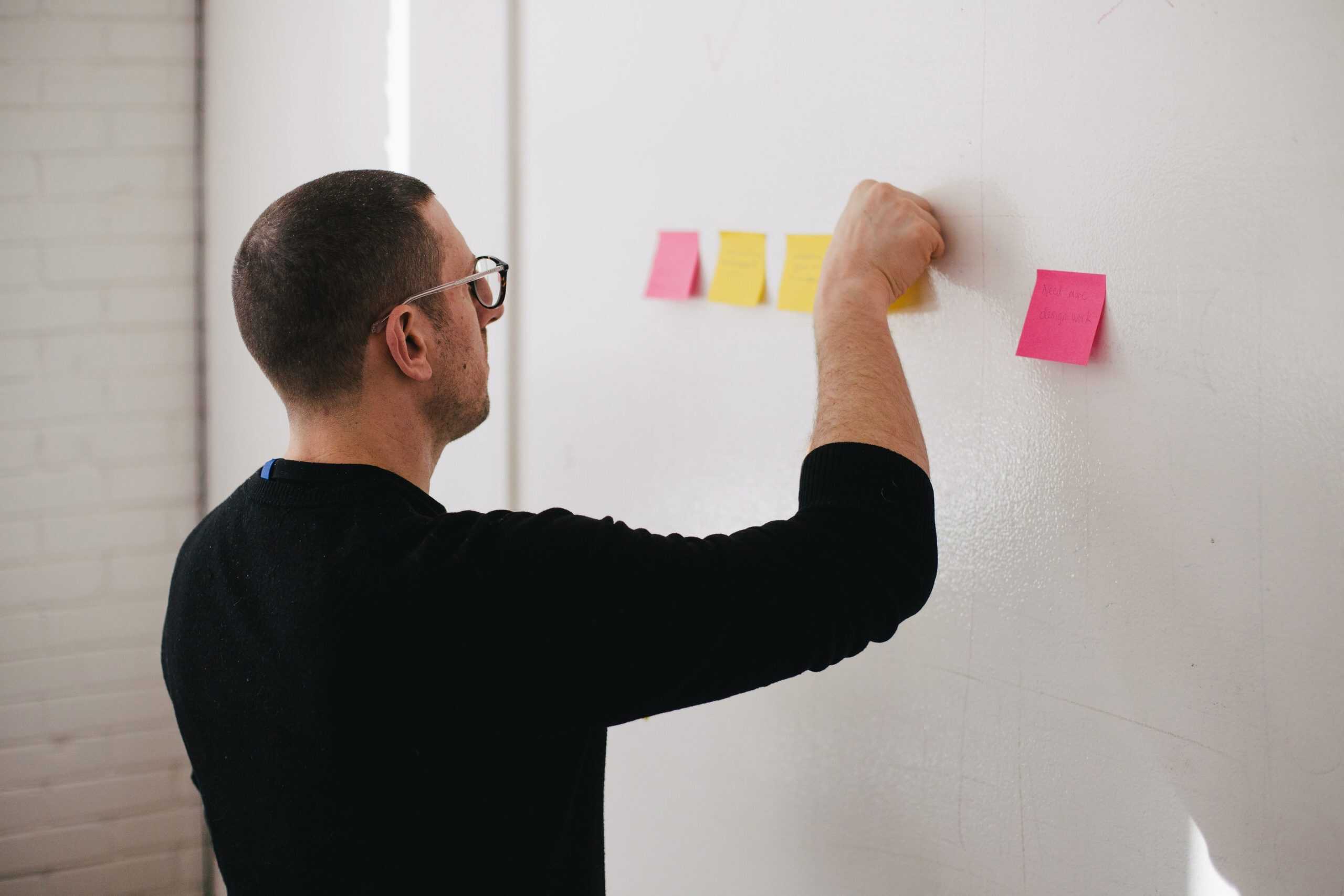 Person attaching postit notes to a whiteboard-1