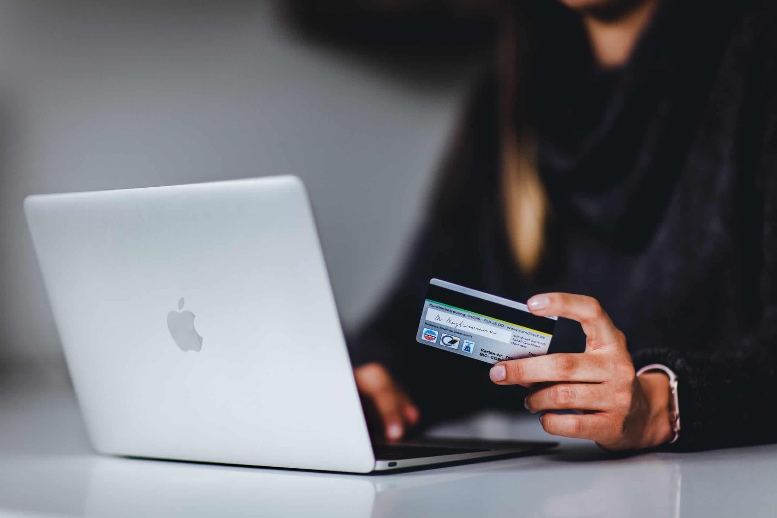 hand holding a credit card and a laptop