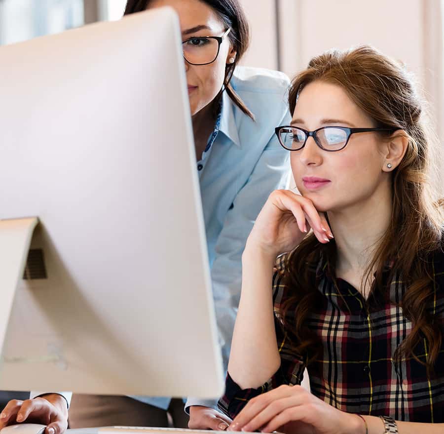 two women looking at a computer desktop monitor